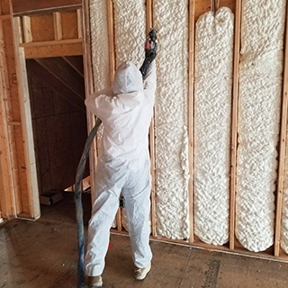 Worker installed spray foam insulation in a home wall.