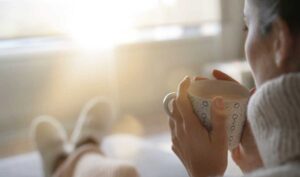 Woman sipping hot drink from a mug on a sunny winter morning.