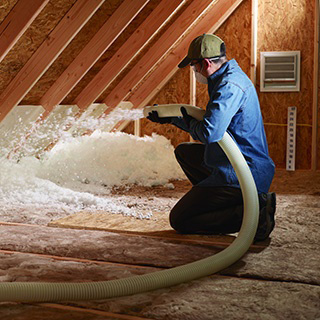 Insulation installer, installing blown-in insulation in home's attic