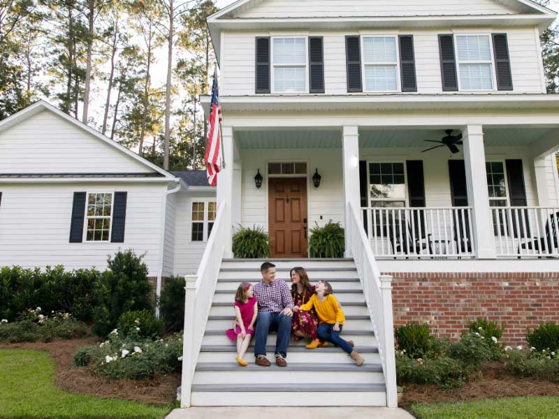 Happy family sitting outside of Arkansas home.