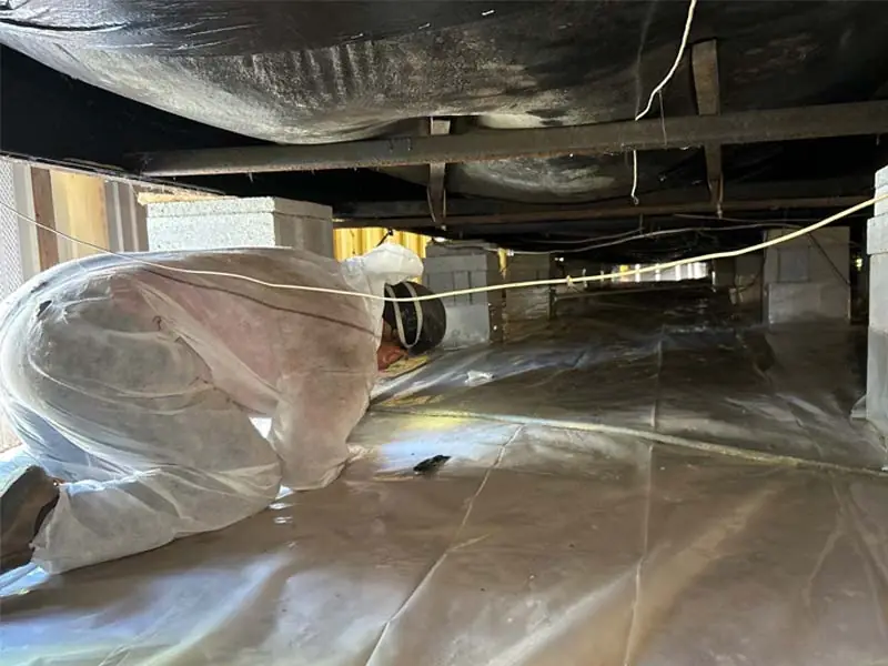 Technician installing crawlspace vapor barrier to control moisture and improve energy efficiency.