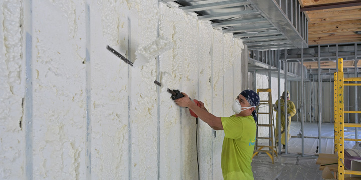G&S Insulating technician applying open-cell spray foam to wall framing in Little Rock, AR.
