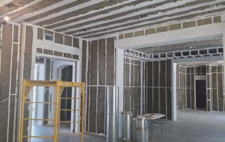 G&S Insulating rock wool batt insulation in interior wall framing and ceiling joists across connected rooms in Little Rock, AR.