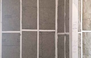 G&S Insulating rock wool batt insulation filling tall wall cavities at a corner beside a framed doorway in Little Rock, AR.