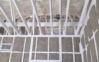 G&S Insulating rock wool batt insulation in upper wall framing below roof trusses and spray foam roof deck in Little Rock, AR.