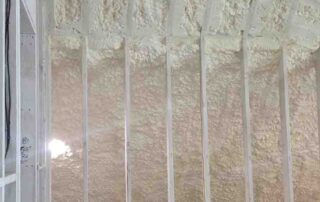 G&S Insulating spray foam insulation on the ceiling deck and exterior wall behind new interior stud framing in Little Rock, AR.